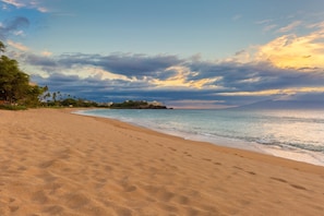 Une plage avec un ciel dégagé et une vue lointaine sur les bâtiments.