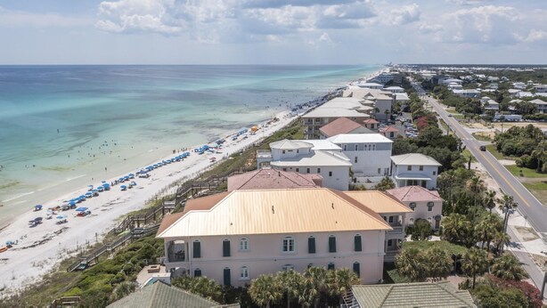 A coastal hotel with a beach view, multiple buildings, and a clear sky.