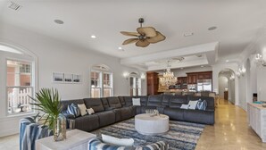 A spacious living room with a sectional sofa, a round coffee table, and a large window.