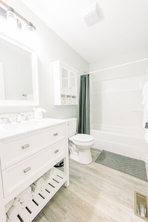 A modern bathroom with a white vanity, a toilet, a shower area, and a bathtub. - #3 Cabin at Red Oak Valley (Canaan Township)