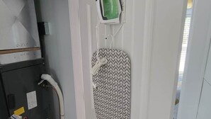 A room with a white door, a vented ceiling, and a small ironing board with an iron on it. - #3 Cabin at Red Oak Valley (Canaan Township)