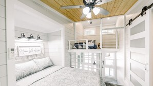 A bedroom with a bed, a ceiling fan, a window, and a built-in shelf. - Tiny Home A at Red Oak Valley (Canaan Township)