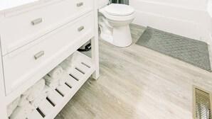 Un baño moderno con tocador blanco, inodoro, zona de ducha y bañera.