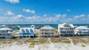 A beachfront property with multiple houses, some with balconies, and a clear view of the ocean. - Gulf Front Beach House | Pet Friendly | Panoramic Coastal Views (Gulf Shores)