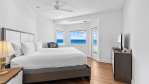 A bedroom with a bed, a desk, a chair, a ceiling fan, and large windows with a view of the ocean. - Gulf Front Beach House | Pet Friendly | Panoramic Coastal Views (Gulf Shores)