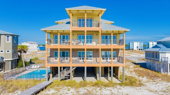 A multi-story beachfront property with a pool, balconies, and a view of the ocean.