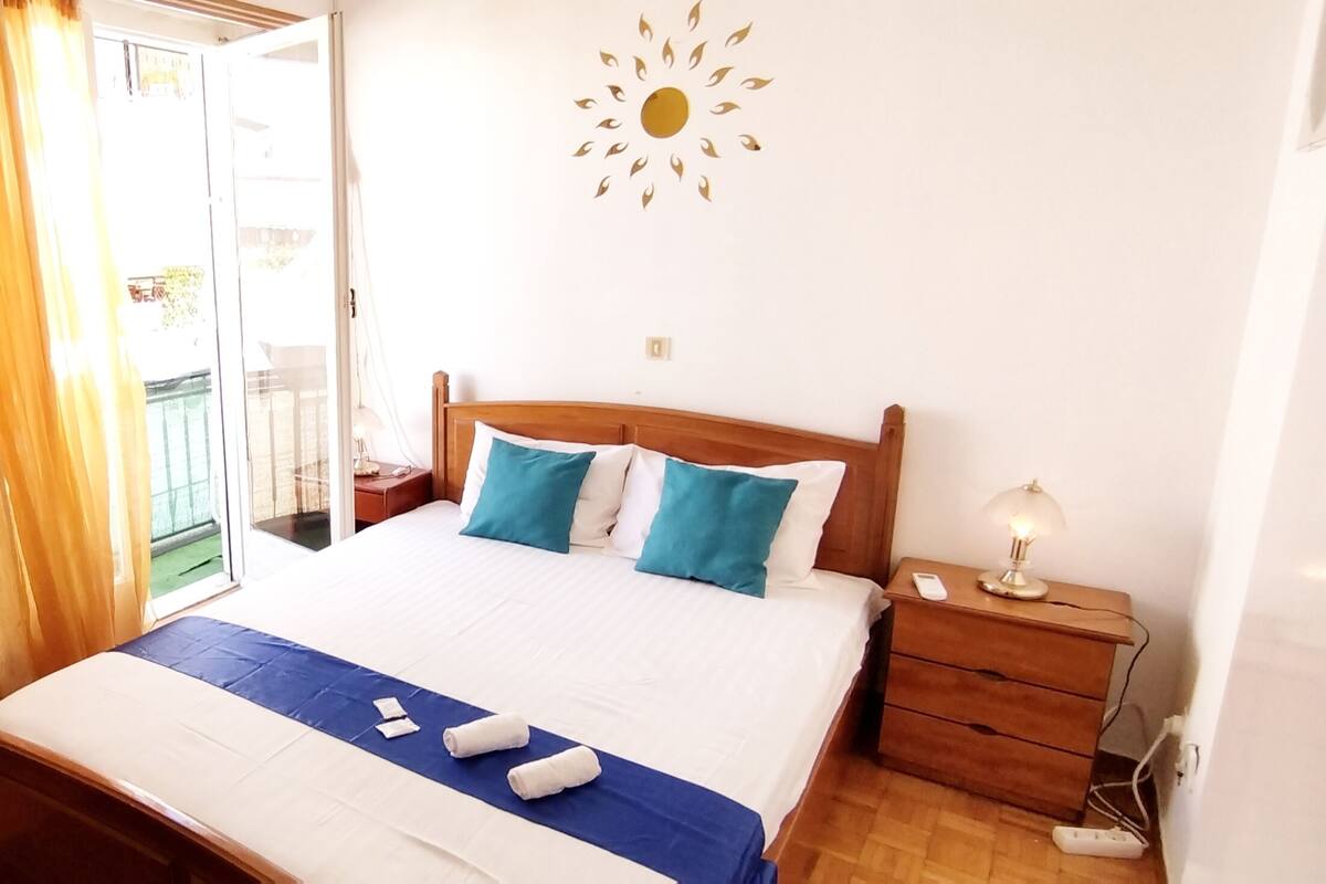 A neatly made bed with blue and white bedding, a wooden headboard, and a bedside table with a lamp.