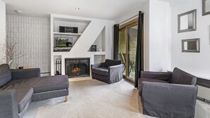 A modern living room with a fireplace, grey sofas, and a white entertainment unit.