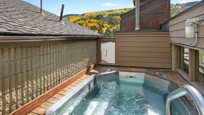 A hot tub on a rooftop with a view of autumn foliage and a hilly landscape.