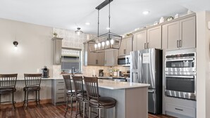 Una cocina moderna con una isla central, electrodomésticos de acero inoxidable y taburetes de bar.