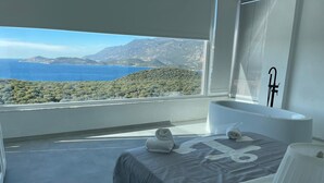 Une chambre moderne dotée d’une grande fenêtre offrant une vue imprenable sur un paysage côtier.