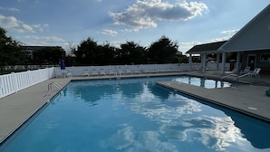 Piscina con señal de prohibido bucear, sillas de descanso y una zona cubierta.