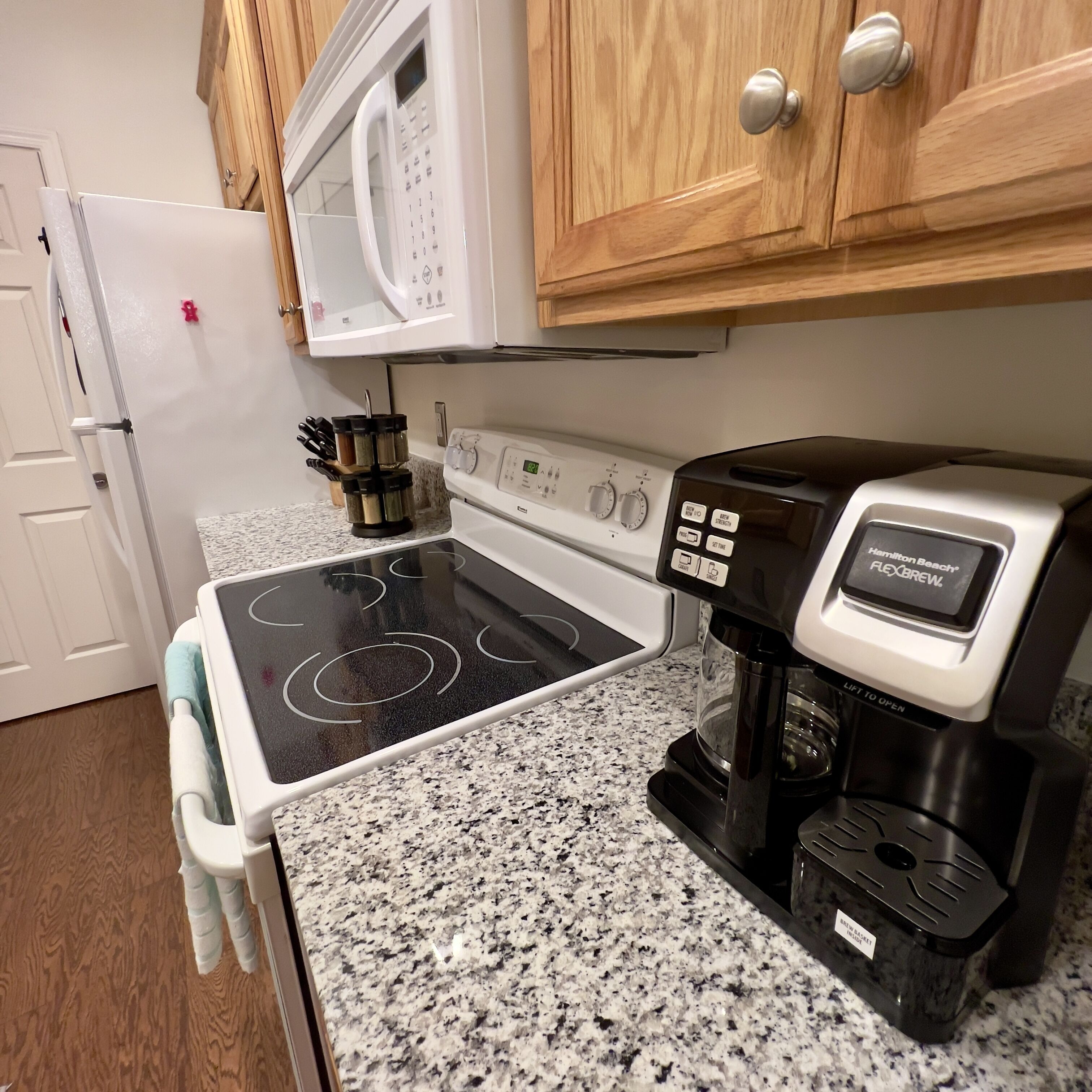Une cuisine équipée d’une cuisinière, d’un four à micro-ondes, d’une machine à café et de meubles de rangement en bois.