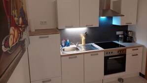 A modern kitchen with white cabinets, a black stove, and a stainless steel sink.