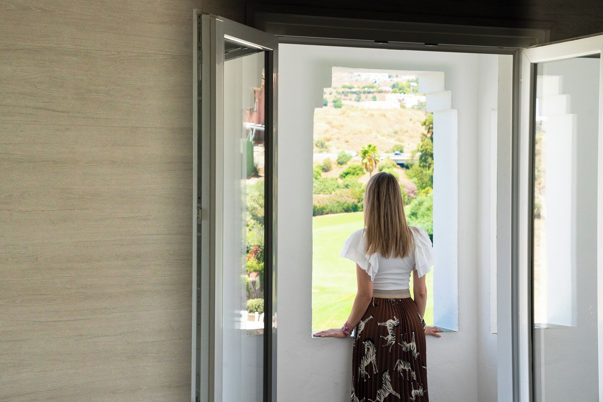 A person standing at a doorway looking out to a garden.