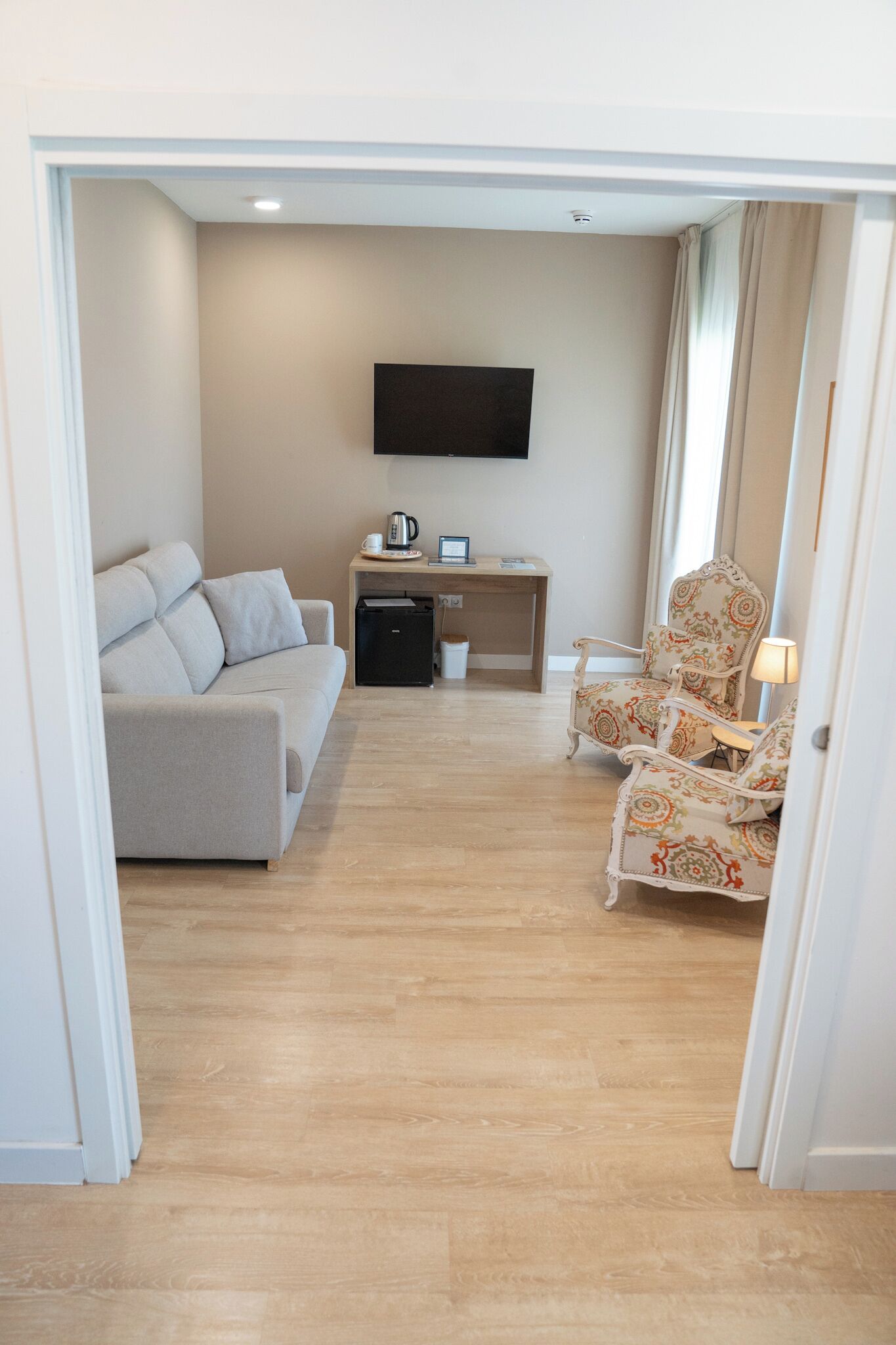 Una sala de estar con sofá, mesa de centro, televisor y un sillón estampado.