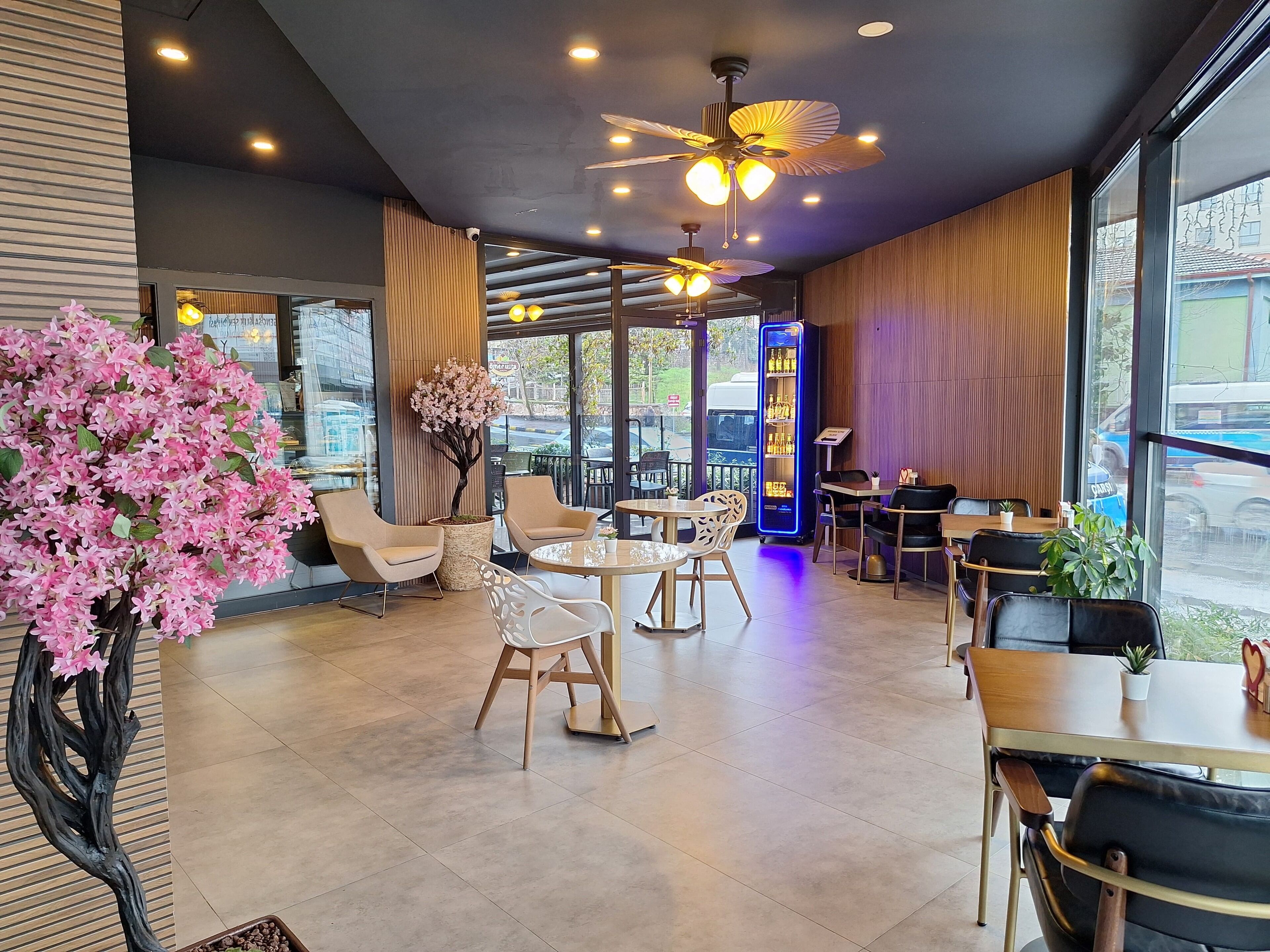 A modern cafe with indoor seating, a ceiling fan, and a vending machine.