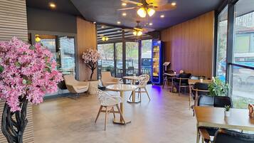 A modern cafe with indoor seating, a ceiling fan, and a vending machine.