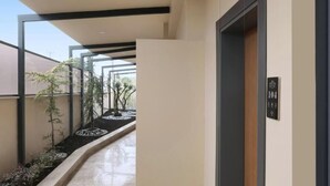 Un pasillo moderno de hotel con un muro de cristal, una puerta de madera y un cartel que indica la habitación 104.