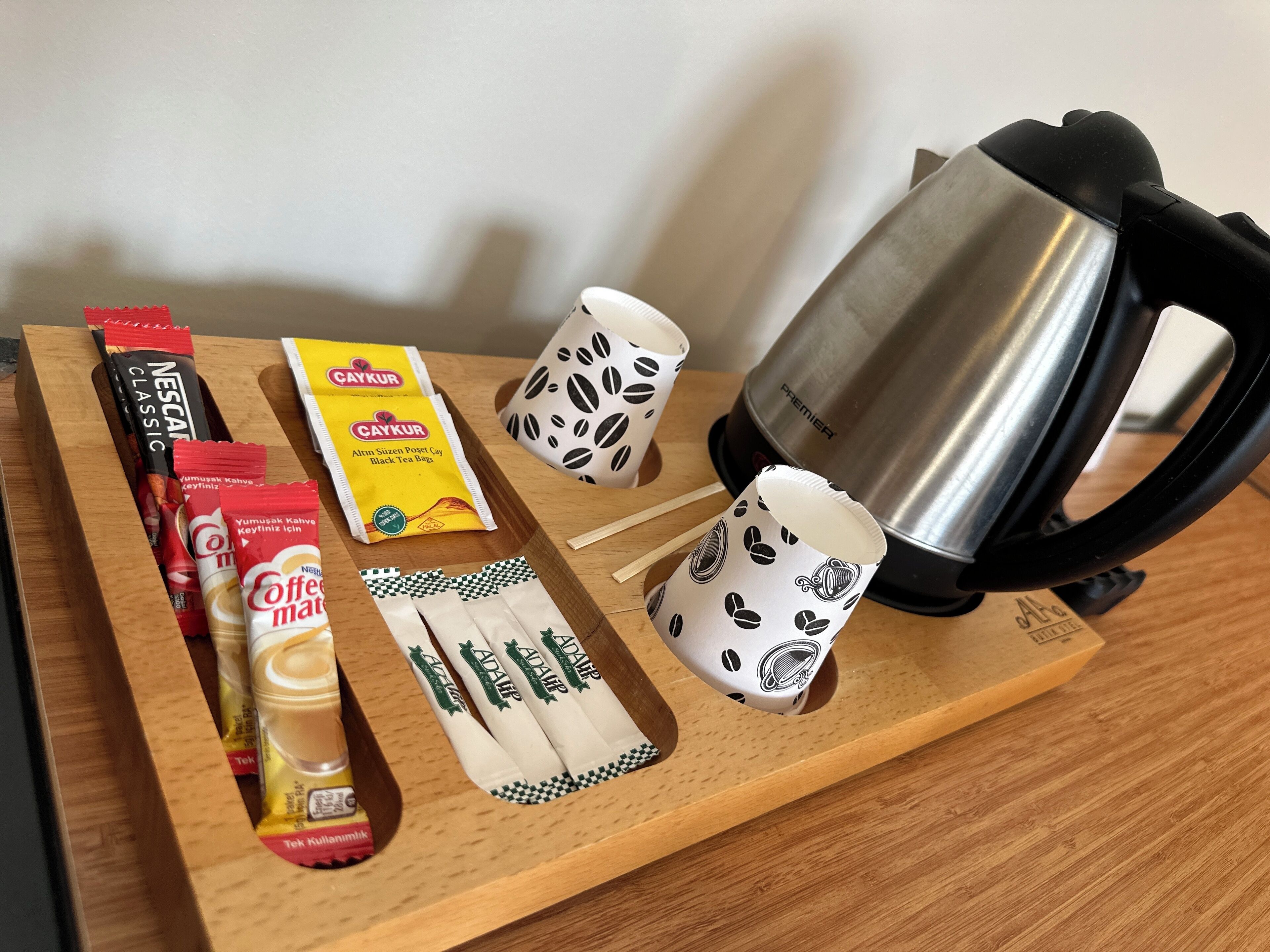 A wooden tray with coffee packets, tea bags, and a coffee maker.