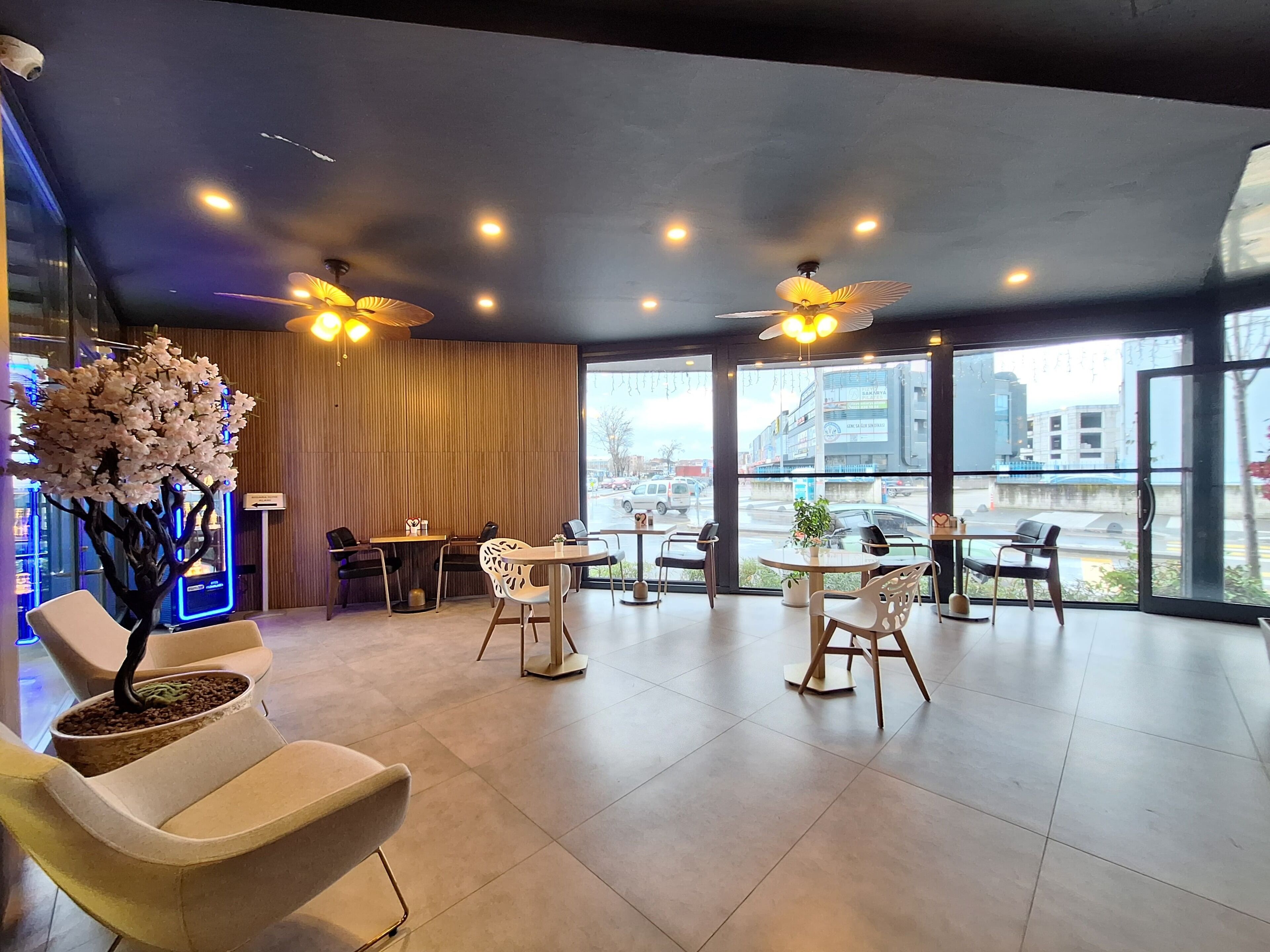 A modern interior with a seating area, large windows, and ceiling fans.