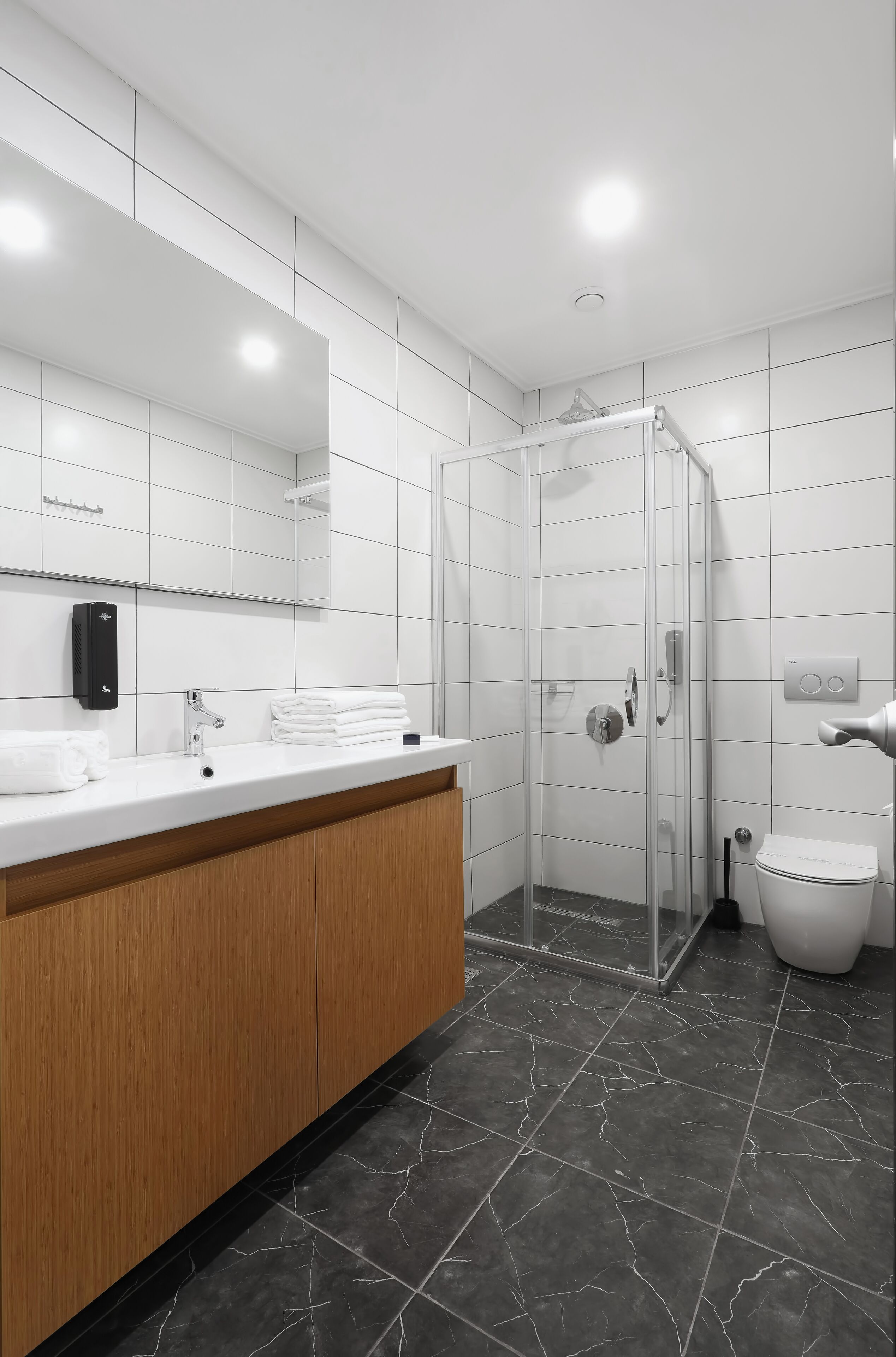 A modern bathroom with a white vanity, a glass shower enclosure, and a toilet.