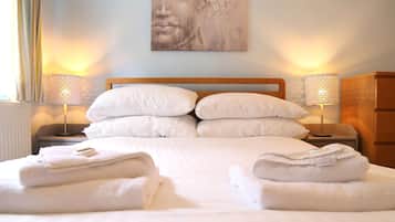 A neatly made bed with white linens and pillows, two bedside lamps, and a wall art piece above the bed.