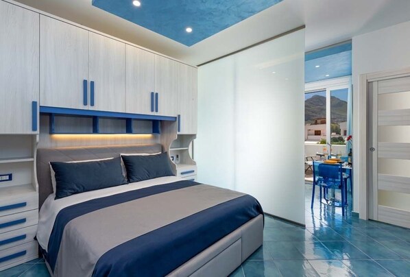 A modern bedroom with a large bed, built-in cabinets, and a view of the outside. - Apartment with swimming pool and terrace by the sea  (San Vito Lo Capo)