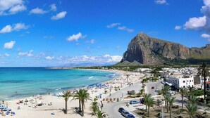 A coastal town with a beach, a prominent mountain, and a mix of residential and commercial buildings.