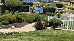 Ein Golfplatz mit einer Fahne auf dem Grün, umgeben von gepflegten Hecken und einem weißen Zaun.