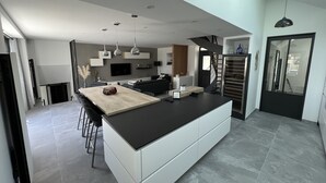 A modern kitchen with a central island, a dining area, and a staircase leading to an upper level.