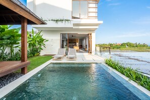 A modern house with a swimming pool, two lounge chairs, and a view of the ocean. - Bali's Quiet Shore - Om Cemagi Villa with Private Pool & Views (Cemagi)