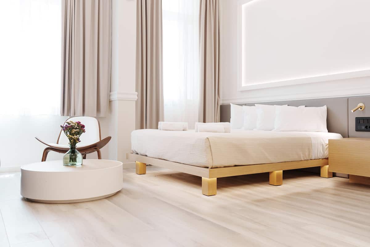 Een moderne slaapkamer met een bed, nachtkastjes, een ronde salontafel en een bloevas.