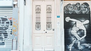 A building facade with a double door, a garage door with a mural, and a number '2' sign. - Agora Athens Suites (Athens)