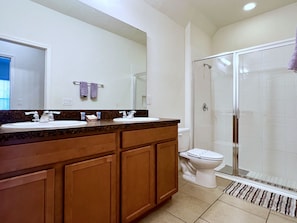 Un bagno con due lavandini, un water e una cabina doccia in vetro.