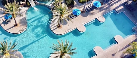A large outdoor swimming pool with multiple sections and palm trees.