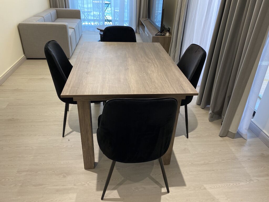 Een eetgedeelte met een houten tafel, zwarte stoelen en een bank op de achtergrond.