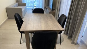 Ruokailutila, jossa on puinen pöytä, mustat tuolit ja taustalla sohva.