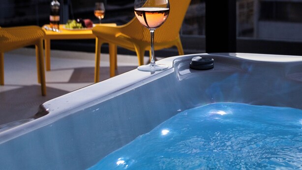 A hot tub with a glass of wine, yellow chairs, and a table with a bottle and a plate of food. - LUX&EASY Athens Downtown Residences (Athens)