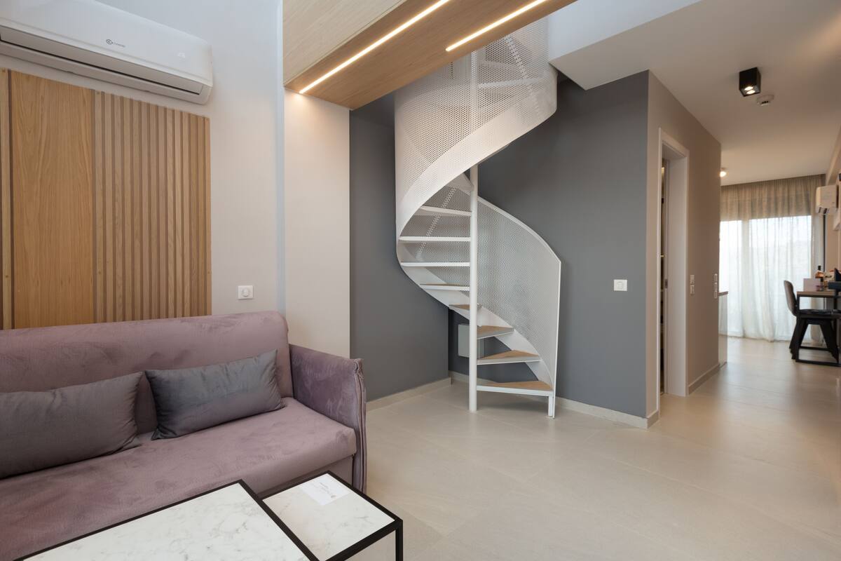 Una sala de estar moderna con una escalera espiral, un sofá y una mesa de centro.