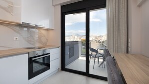 A modern kitchen with a built-in oven and a view of a balcony with a table and chairs. - LUX&EASY Athens Downtown Residences (Athens)