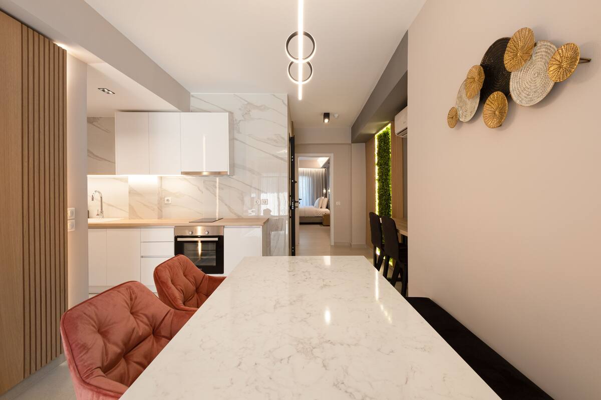 Una cocina moderna con encimera de mármol, un comedor con una mesa grande y una pieza decorativa en la pared.