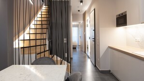 A modern kitchen with a wooden staircase, a marble countertop, and a built-in oven. - LUX&EASY Athens Downtown Residences (Athens)