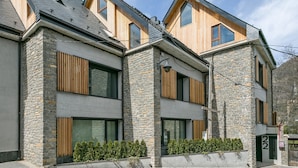 A modern two-story house with stone and wood exterior, large windows, and a well-maintained garden. - Luderna - Casa Peregrí (Arties)
