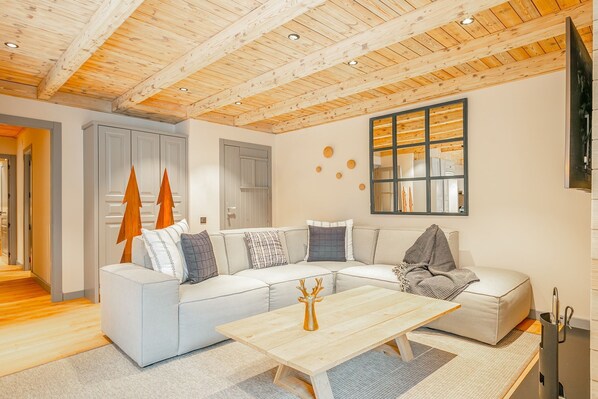 A modern living room with a wooden ceiling, a large window, and a sectional sofa.