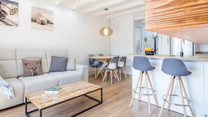 A modern living room with a sofa, coffee table, and a dining area with chairs and a table. - Luderna - Apartamento con terraza Mirador Salardu (Naut Aran)