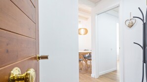 A wooden door with a brass handle, a white door with a heart-shaped decoration, and a hallway leading to a dining area with a hanging light fixture. - Luderna - Apartamento con terraza Mirador Salardu (Naut Aran)