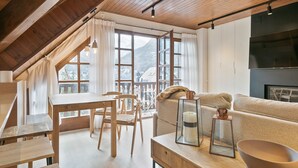 Ein gemütliches Zimmer mit Holzboden, einem Esstisch mit Stühlen, einer Couch und einem Kamin.