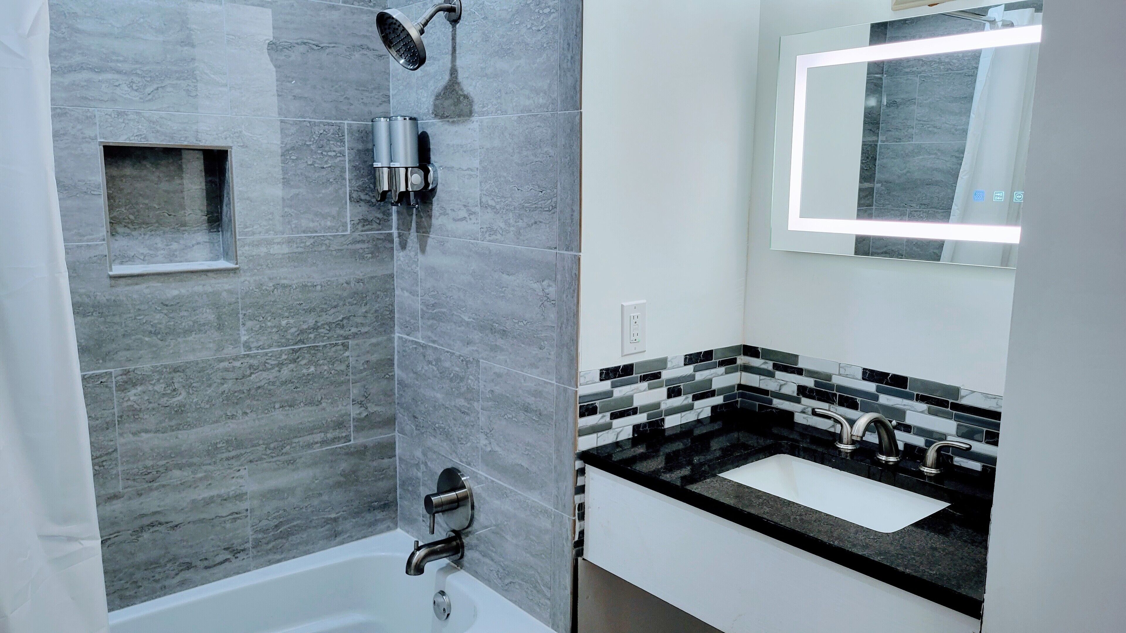 Un bagno moderno con doccia, lavandino e specchio.