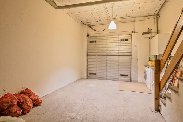 A clean, empty garage with a concrete floor, a closed metal garage door, and a single hanging light fixture.